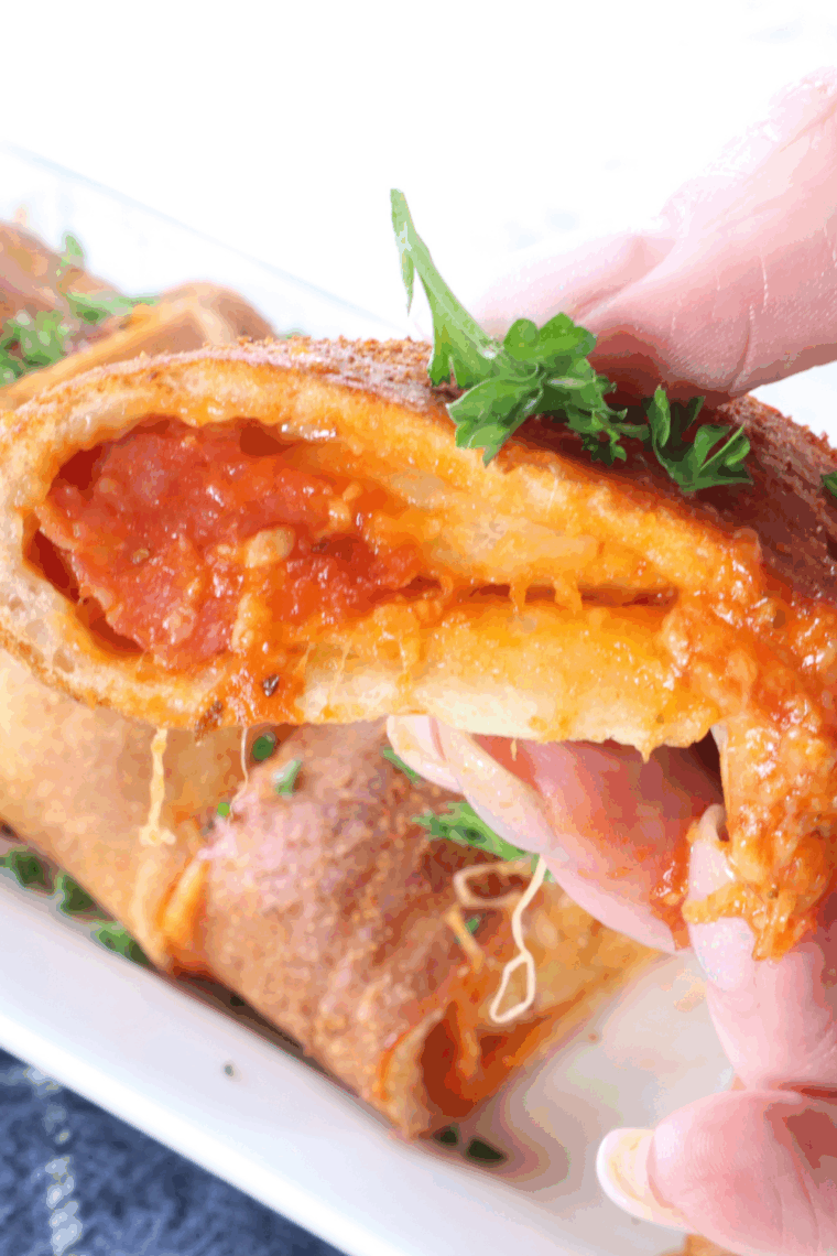 Air Fryer Pepperoni Stromboli sliced open, showing melted cheese and layers of pepperoni inside.