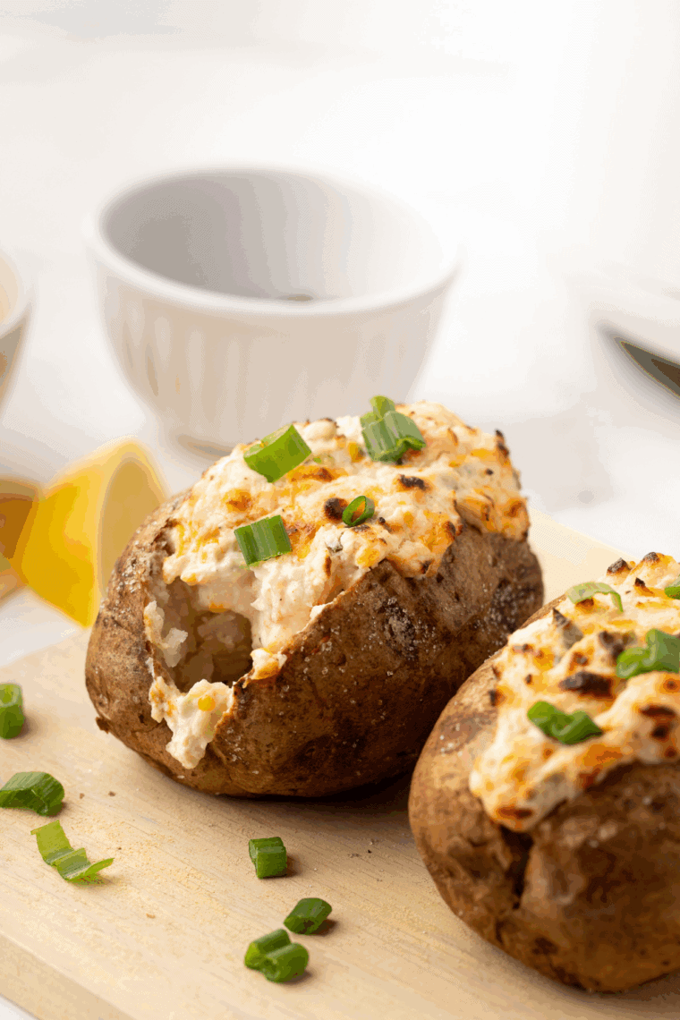 Golden baked potato with crispy skin, topped with butter and fresh herbs