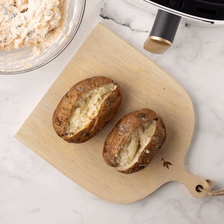 Golden baked potato with crispy skin, topped with butter and fresh herbs