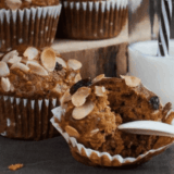 Close-up of an air fryer morning glory muffin with a batch cooling on a wire rack behind
