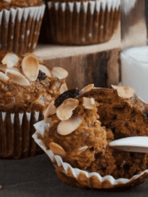 Close-up of an air fryer morning glory muffin with a batch cooling on a wire rack behind