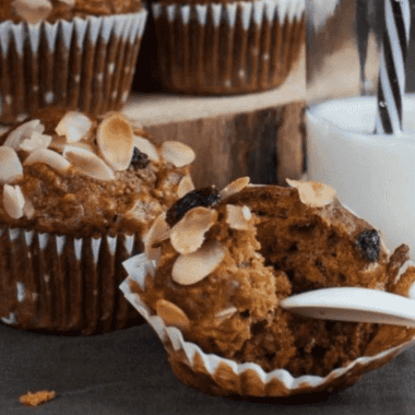 Close-up of an air fryer morning glory muffin with a batch cooling on a wire rack behind