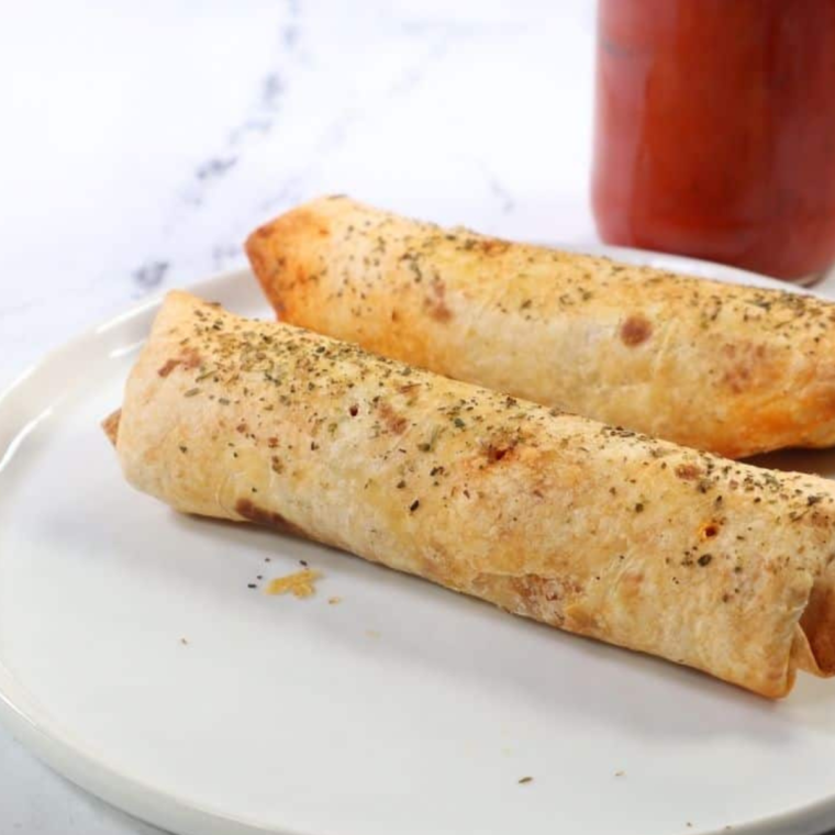 Sliced air fryer pizza sticks showing gooey cheese and pepperoni filling.