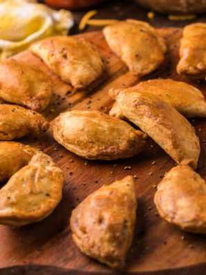 Golden air fryer beef empanadas stacked on a white plate with salsa for dipping