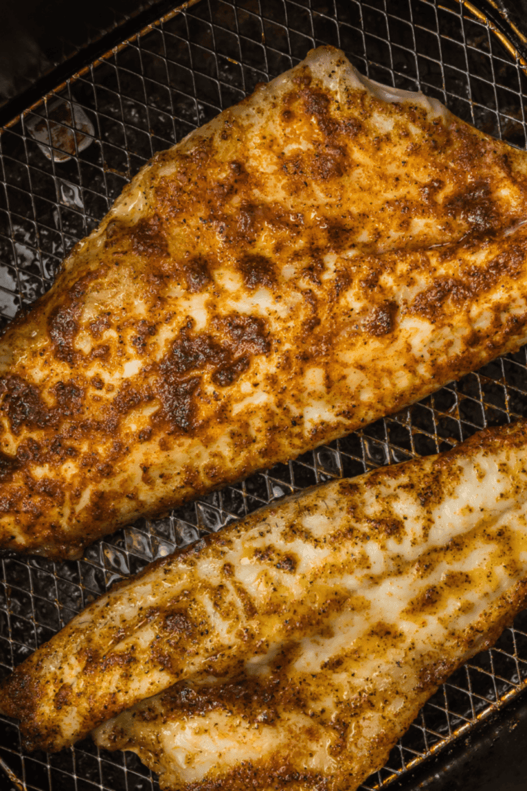 Golden, crispy air fryer branzino fillets and whole fish served with lemon wedges and fresh herbs.