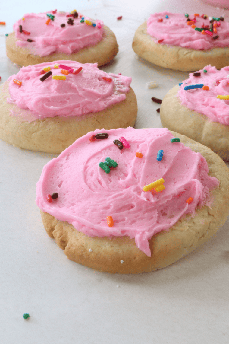 Plate of Air Fryer Copycat Lofthouse Cookies topped with pink frosting and colorful sprinkles.
