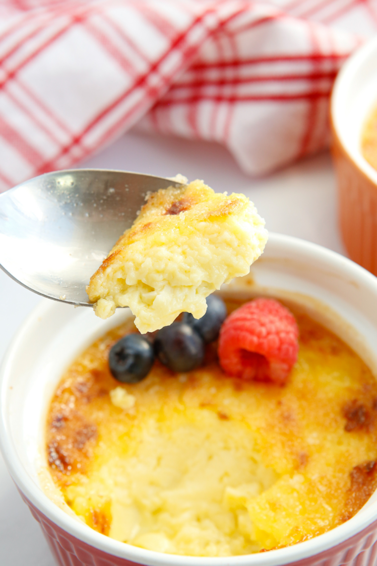Creme brulee topped with fresh raspberries beside a spoon