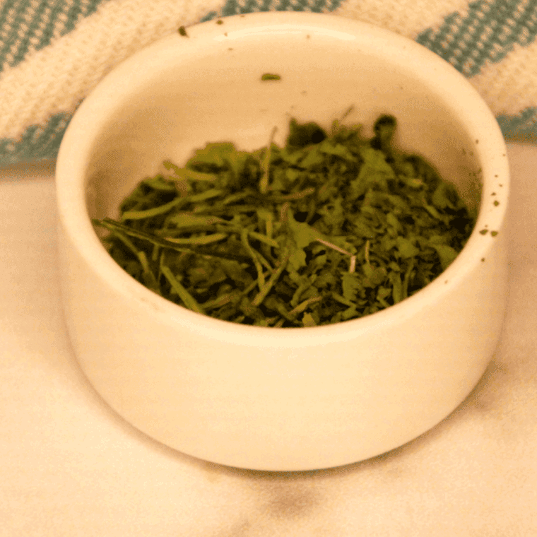 Fresh cilantro being dehydrated in the air fryer, ready for long-term storage.