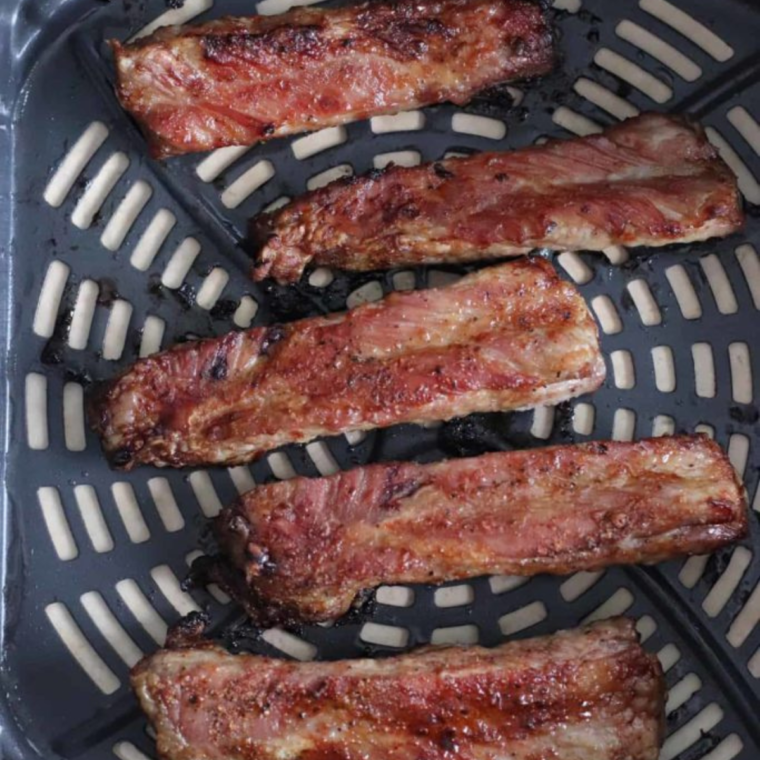 "Ribs cooking in the air fryer until tender and golden brown."