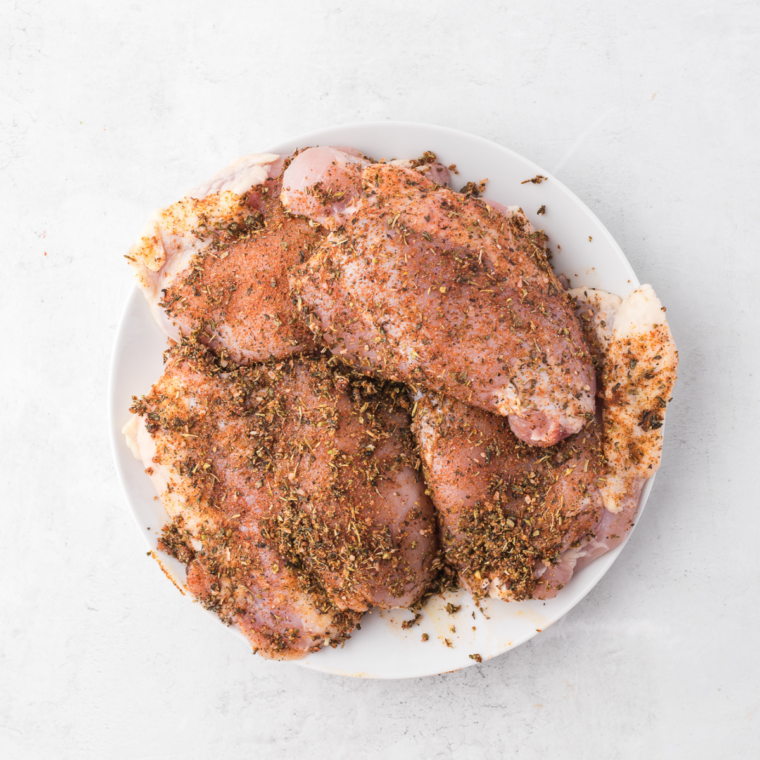 Boneless chicken thighs coated in jerk marinade in a glass bowl