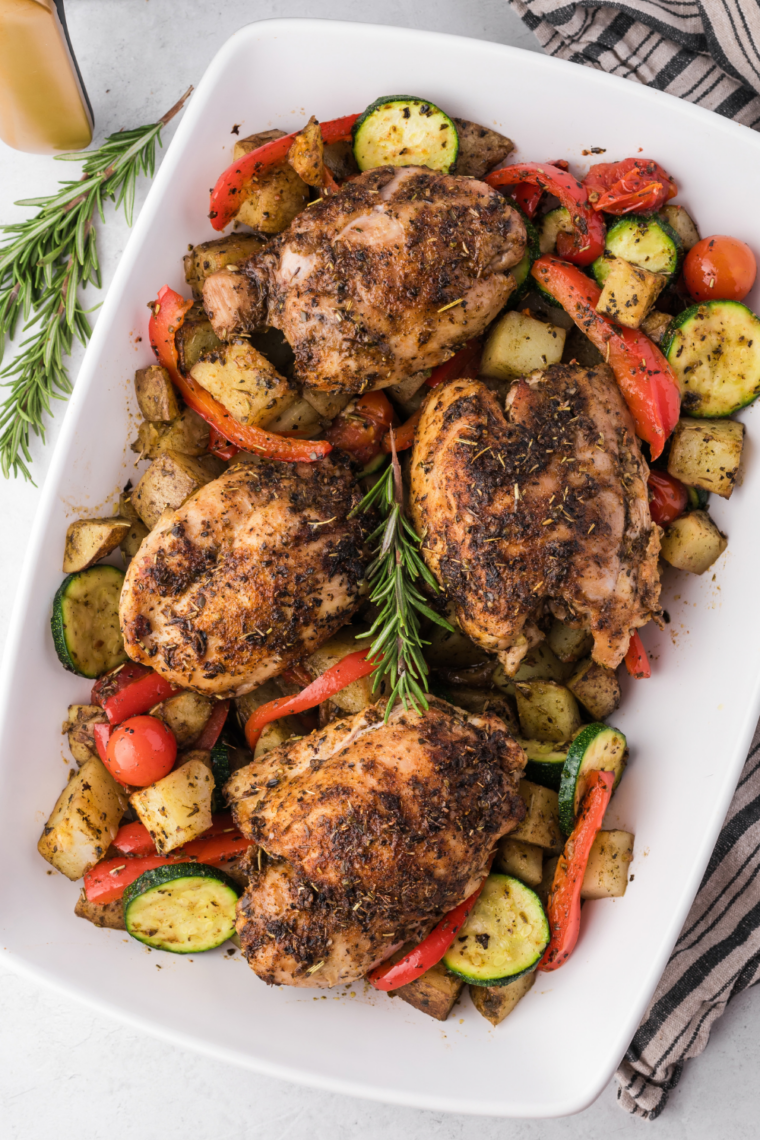 Jerk chicken thighs served with tomatoes, red peppers and zucchini