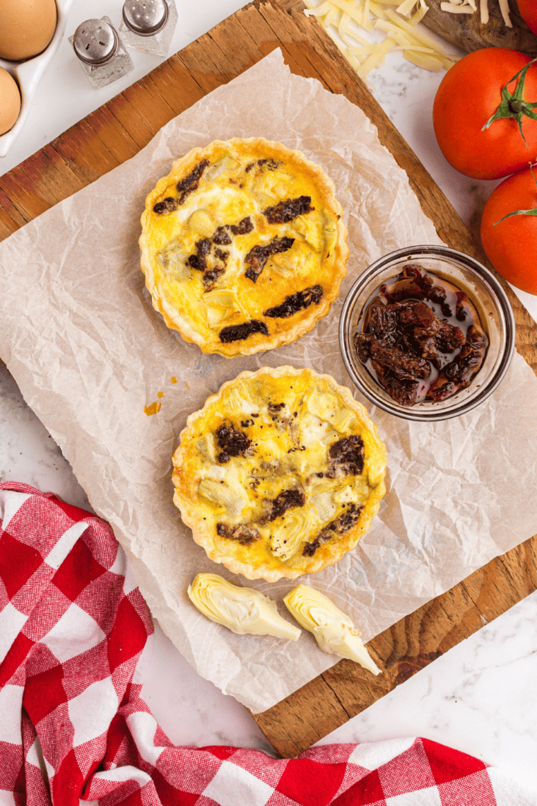 Overhead view of two air fryer sun-dried tomato and artichoke quiches on a plate