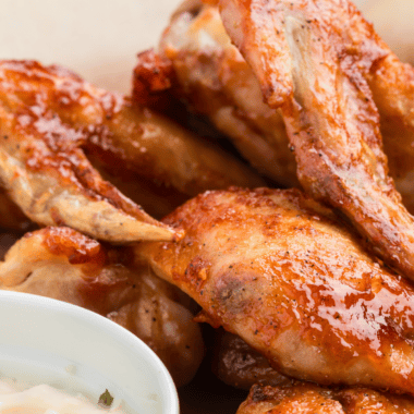 Crispy Wingstop-style mild chicken wings coated in buttery sauce served on a plate with dipping sauce.