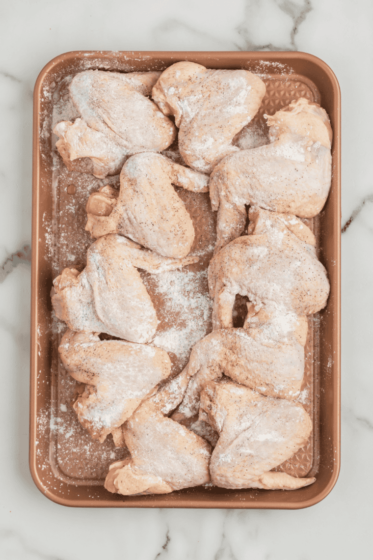 Tossing chicken wings with seasoning in a large bowl