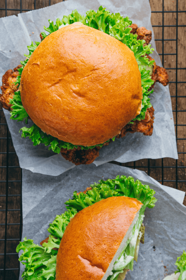 Golden crispy Wingstop-style chicken sandwich with lettuce, tomato, pickles, and sauce on a toasted bun, ready to serve.