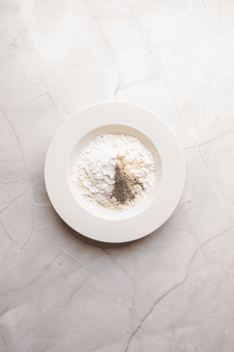 Bowl of seasoned flour and cornstarch mixture ready for coating chicken.