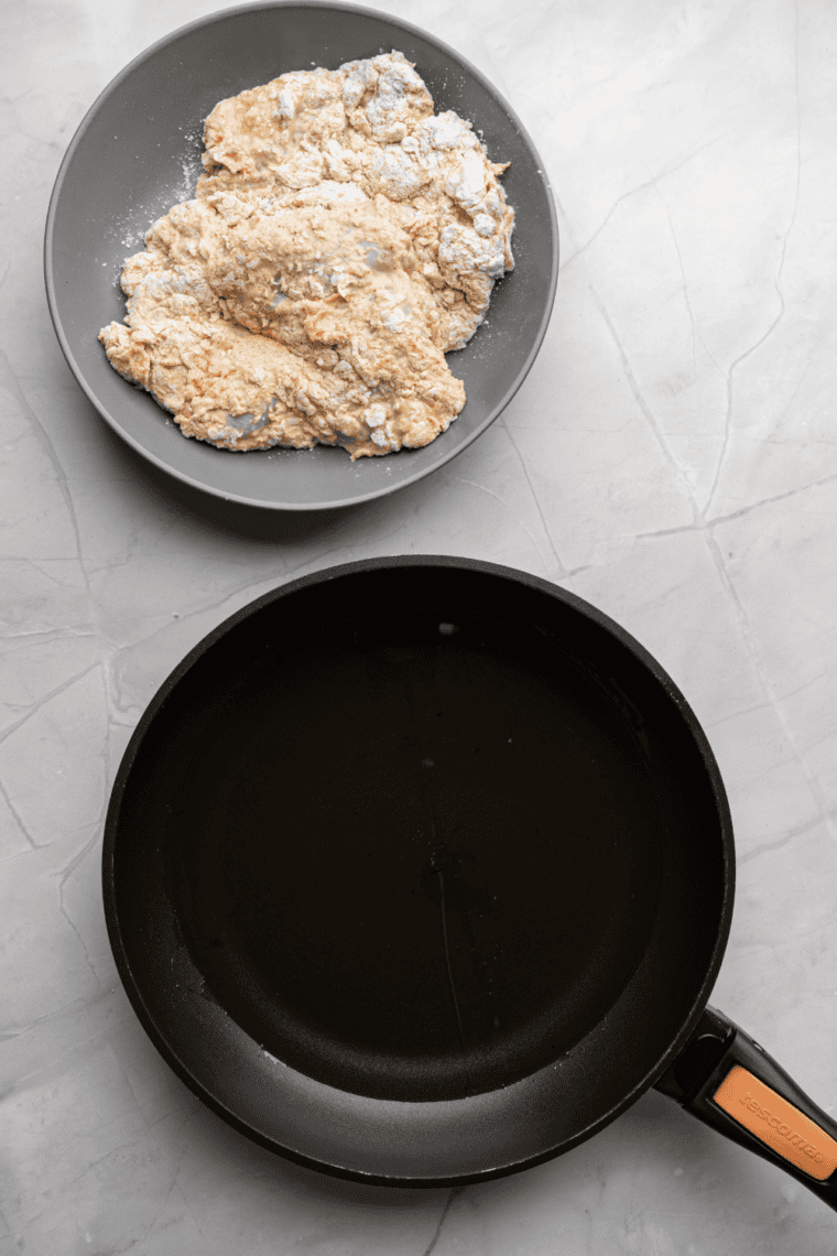 Chicken pieces being dredged in seasoned flour mixture for an even coating.