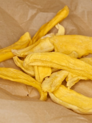 Sliced mango pieces dehydrating in an air fryer, turning golden and chewy as a healthy homemade fruit snack.