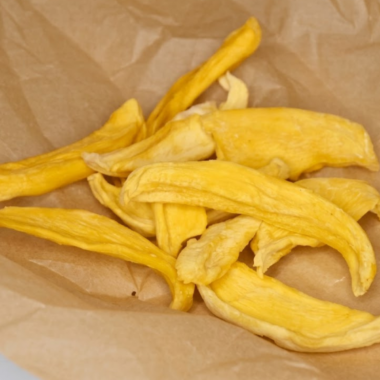 Sliced mango pieces dehydrating in an air fryer, turning golden and chewy as a healthy homemade fruit snack.