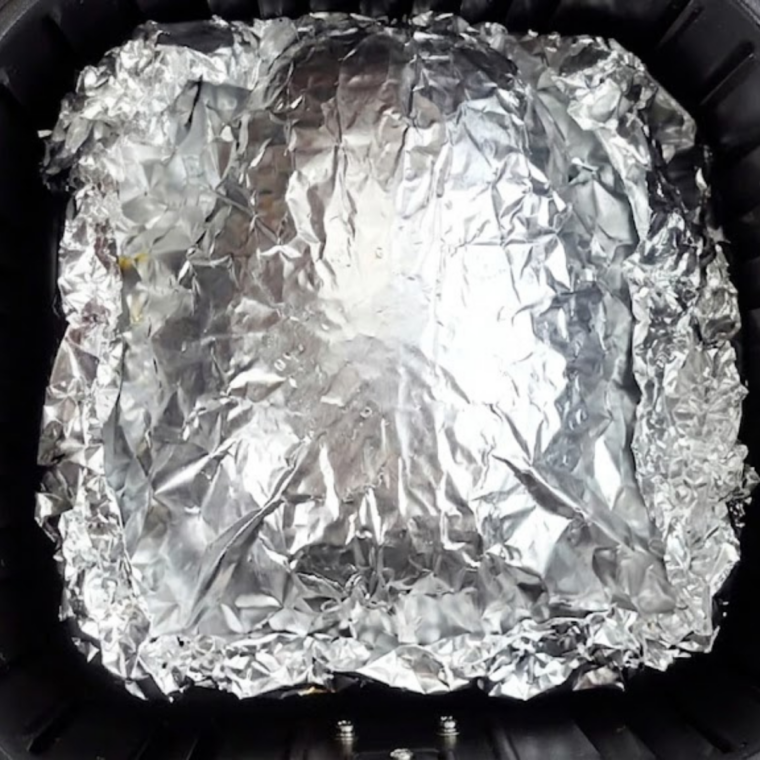 Foil-wrapped brisket placed in air fryer basket cooking at 360&deg;F for slow steam braising.