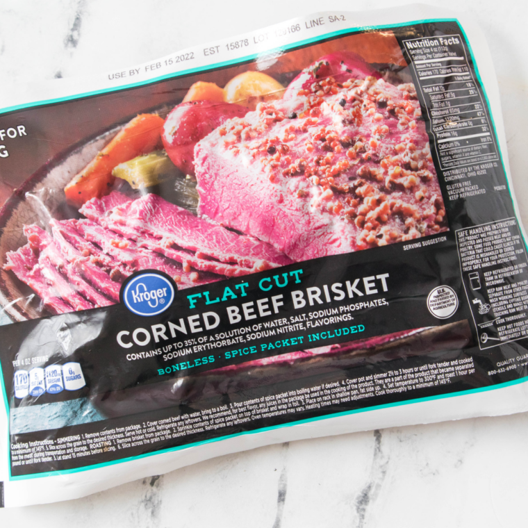 Corned beef brisket being rinsed under cold water and patted dry with paper towels before adding mustard glaze.