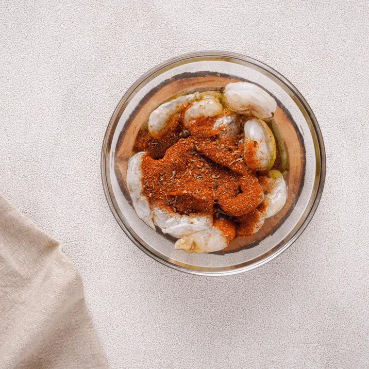Tossing shrimp with Cajun seasoning, salt, and black pepper until coated
