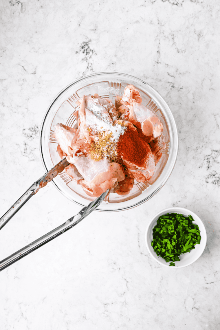 Tossing chicken wings with salt, pepper, paprika, garlic, and cayenne