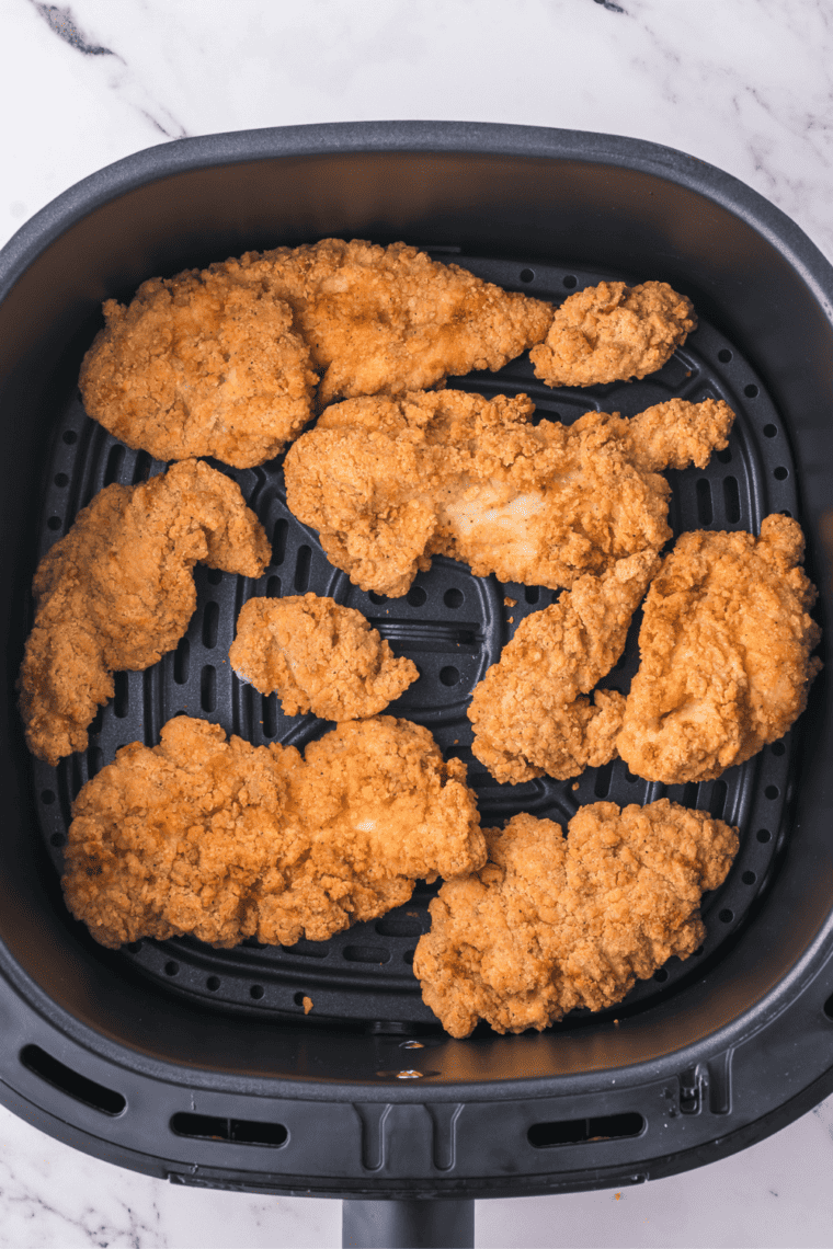 Foster Farms chicken strips cooking in air fryer with crispy breading forming, ready for a quick shake halfway through.