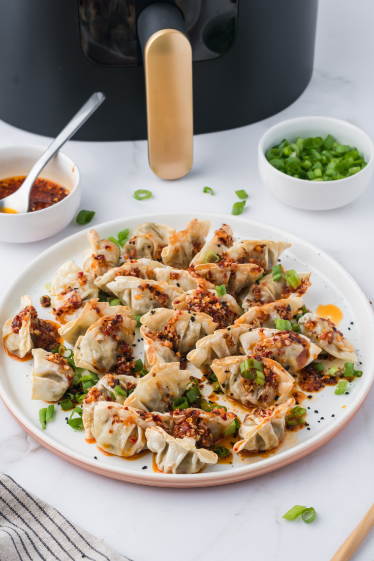Close-up of air fryer cooked Trader Joe&rsquo;s potstickers garnished with sesame seeds and green onions