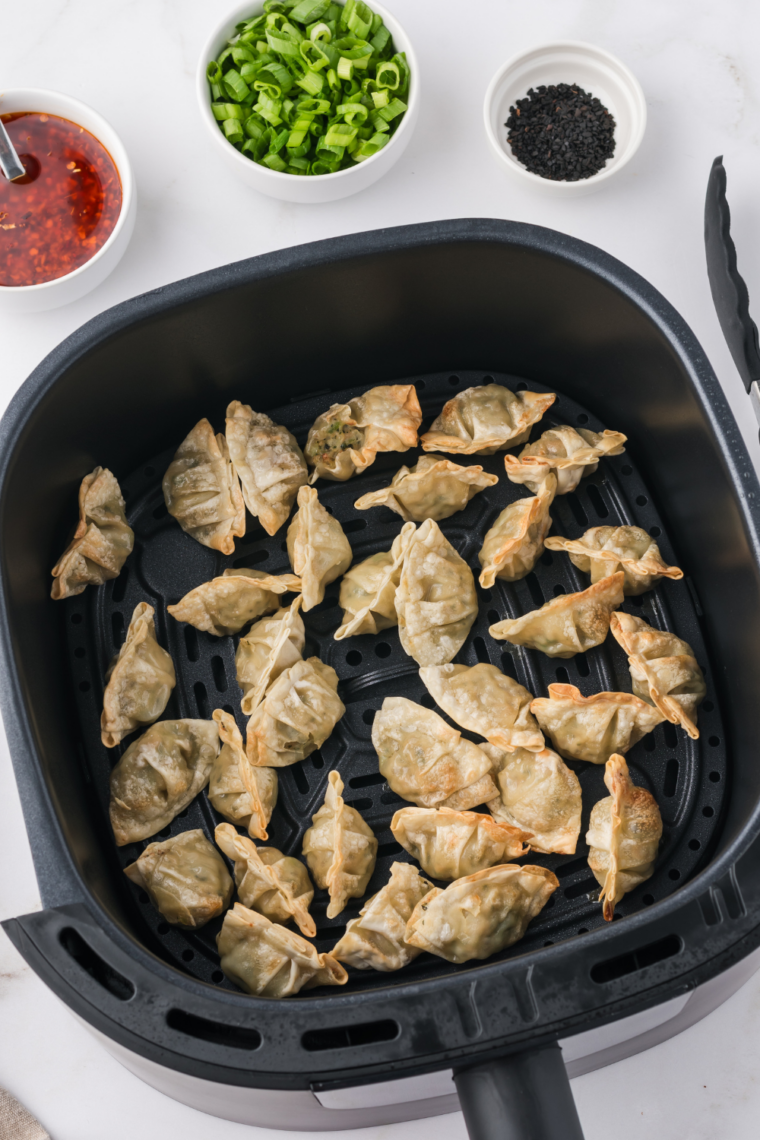 Air fryer potstickers topped with chopped green onions and sesame seeds for garnish