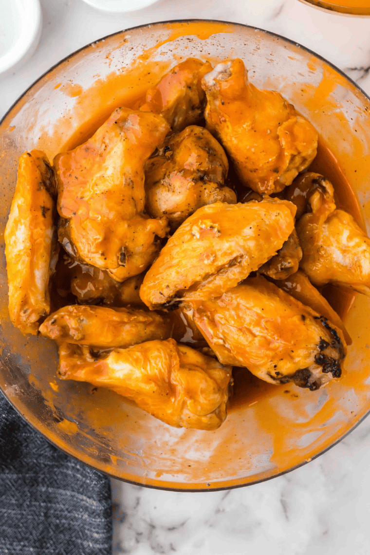 Crispy Wingstop Original Hot copycat chicken wings coated in spicy buffalo sauce served on a plate with dipping sauce.