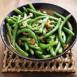 bowl of green beans with almonds on a trivet