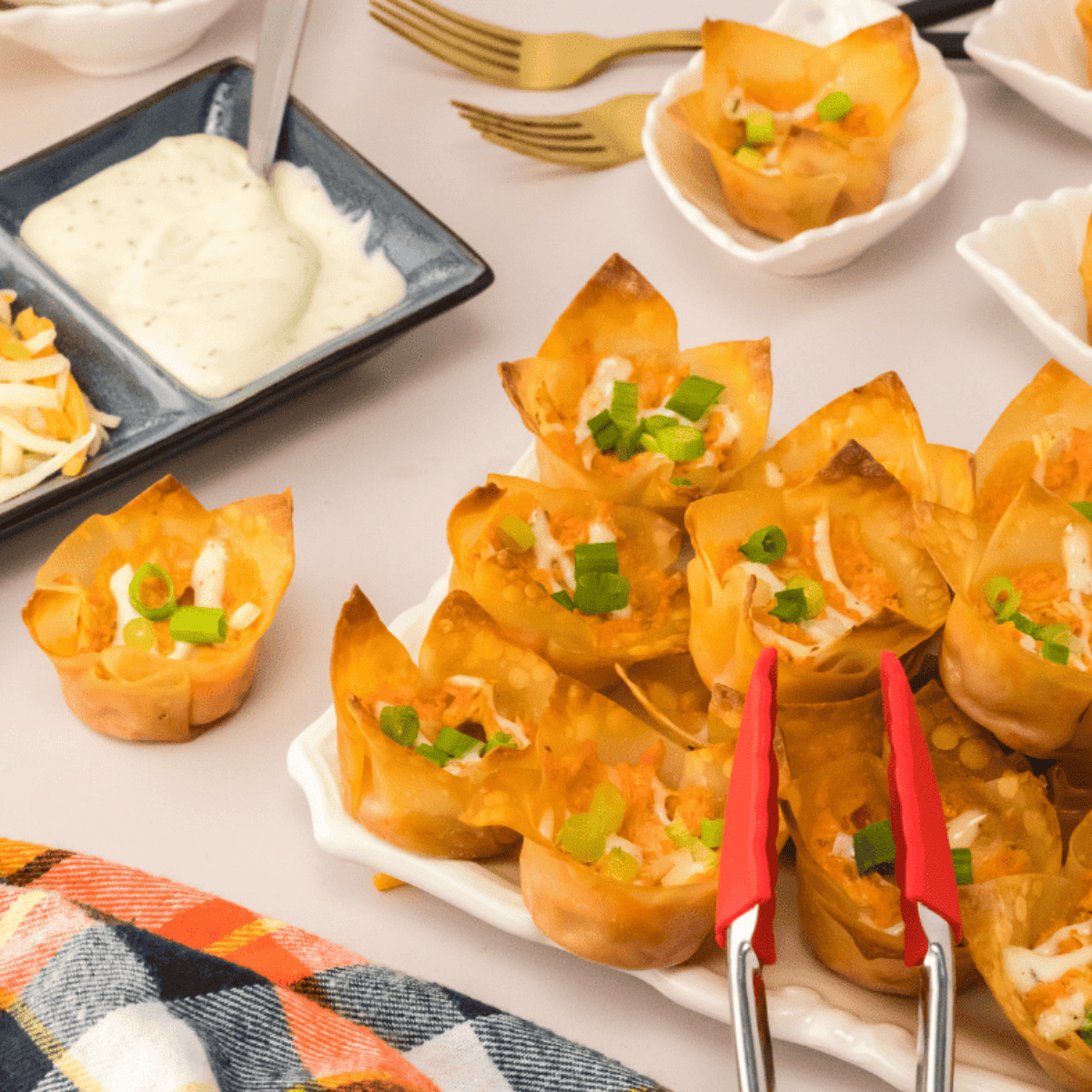 Crispy air fryer buffalo chicken wontons on a plate, filled with spicy chicken, melted cheese, and garnished with green onions, ready to serve.