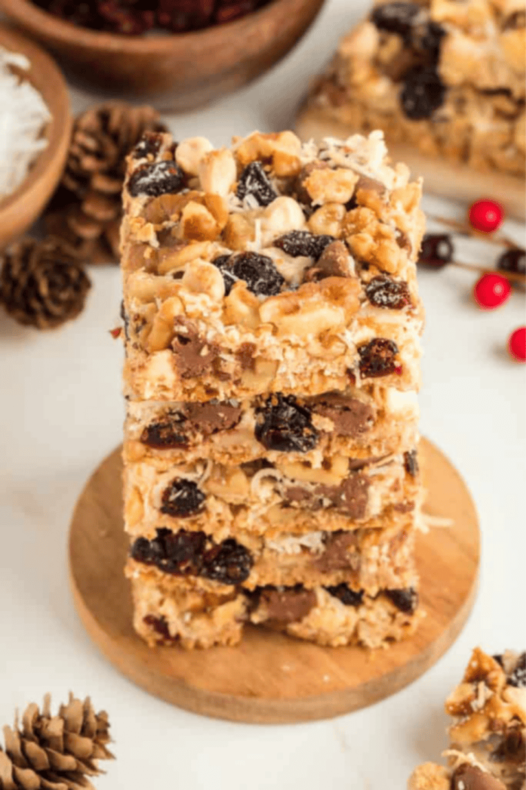 A stack of sliced Cranberry Magic Cookie Bars showing layers of graham cracker crust, melted white chocolate, vibrant red dried cranberries, and golden toasted shredded coconut.