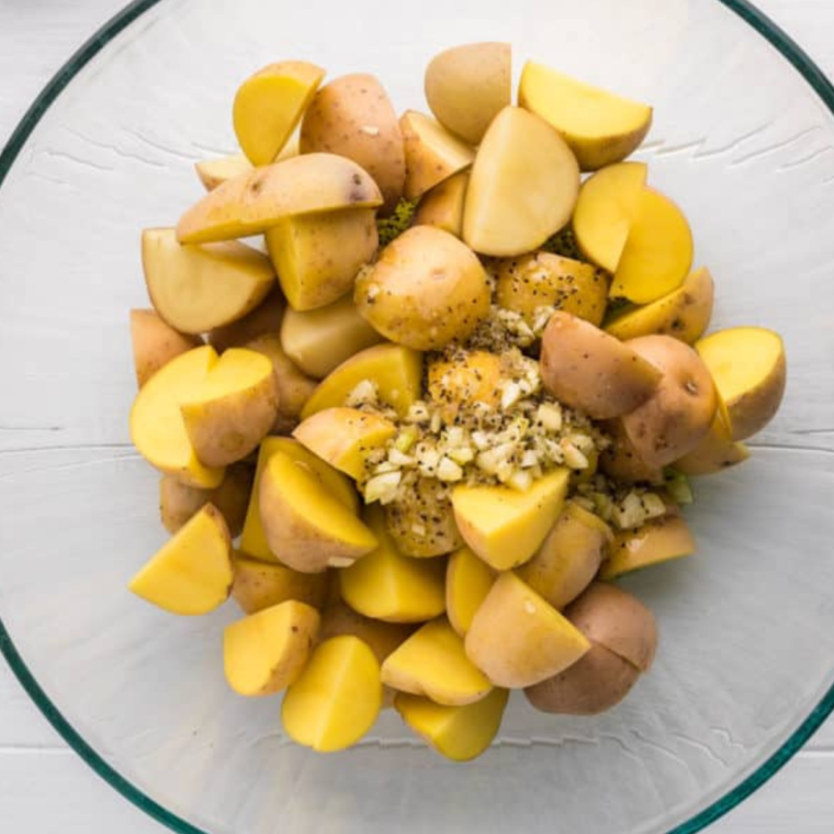 Chopping fresh potatoes and seasoning for Greek-style potatoes.