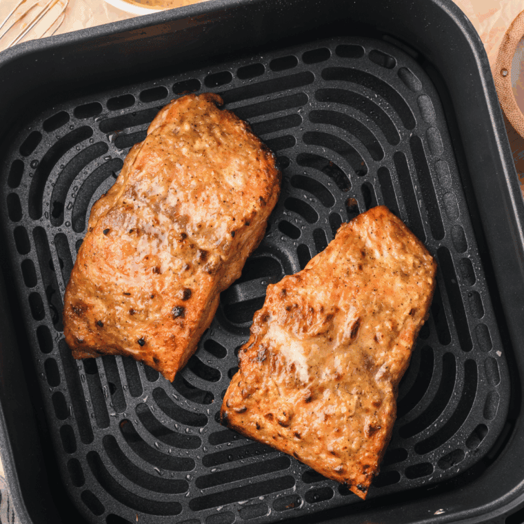 Salmon fillets arranged in a single layer in the air fryer basket, spaced apart for even cooking