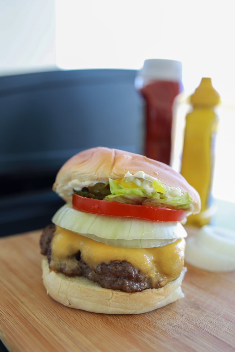 Frozen hamburger patties cooking on a Blackstone griddle with crispy seared edges