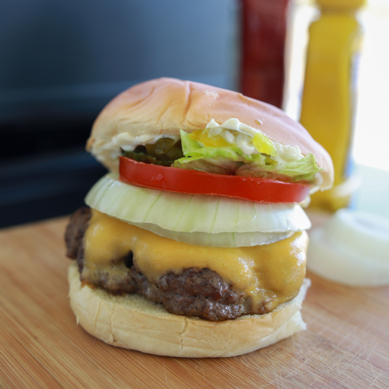 Close-up of frozen burger patties sizzling on a Blackstone griddle surface