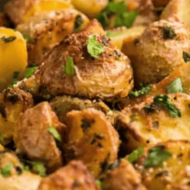 Overhead shot of crispy Air Fryer Greek Lemon Potatoes in a serving bowl with lemon and herbs.