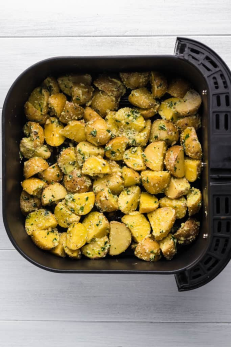 Placing seasoned potatoes in the air fryer basket for cooking.