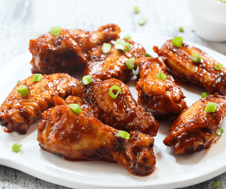 honey barbecue wings on white plate with green onion garnish