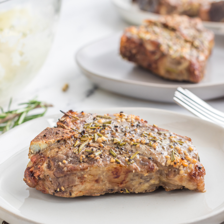 Air fryer lamb chops plated with fresh rosemary, sliced to show a tender medium-rare interior