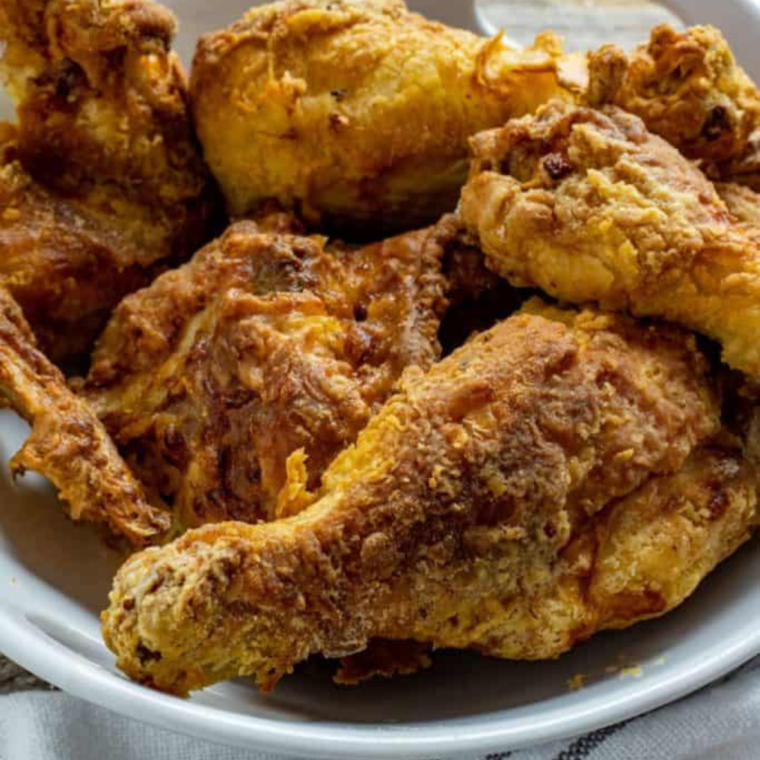 Close-up of a piece of Air Fryer Popeyes Fried Chicken, highlighting its juicy meat and crunchy texture.