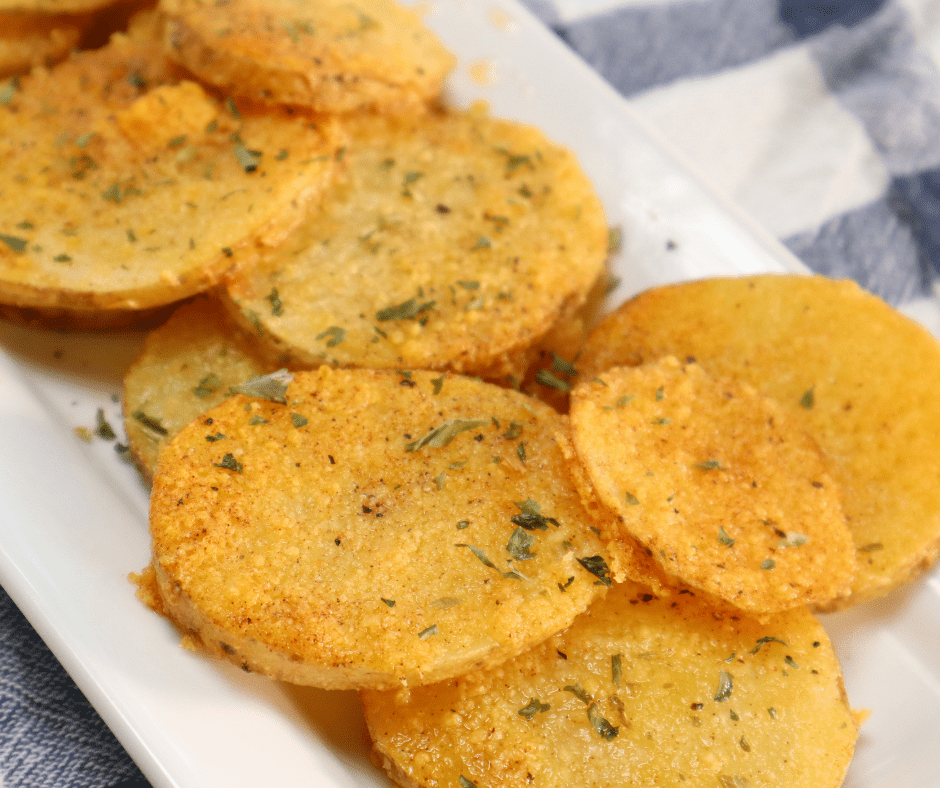 Air Fried Potato Slices on a plate with seasonings and herbs, on a blue checkered napkin
