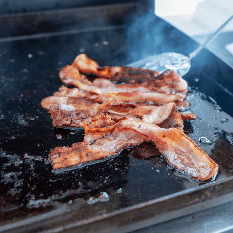 Cooking crispy bacon on the Blackstone griddle for a perfect texture.