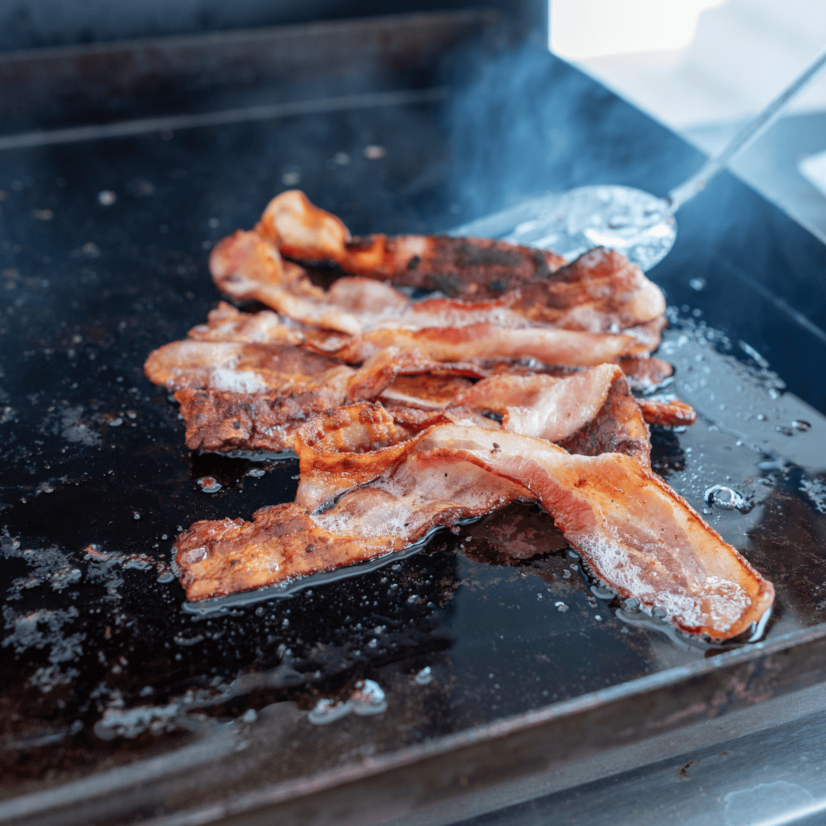 Cooking crispy bacon on the Blackstone griddle for a perfect texture.
