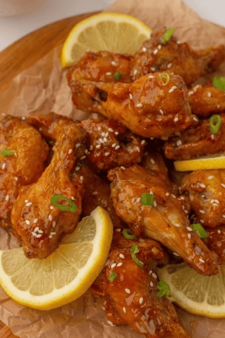 Copycat Hooters lemon pepper wings on a white plate with lemon wedges and a side of ranch