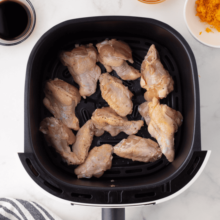 Chicken wings arranged in a single layer in an air fryer basket, cooked golden and crisp for copycat Hooters lemon pepper wings