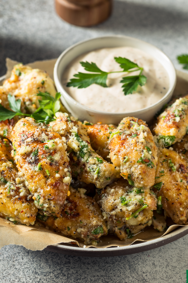 Keto Air Fryer Garlic Parmesan Wings on a plate with fresh herbs and sauce.