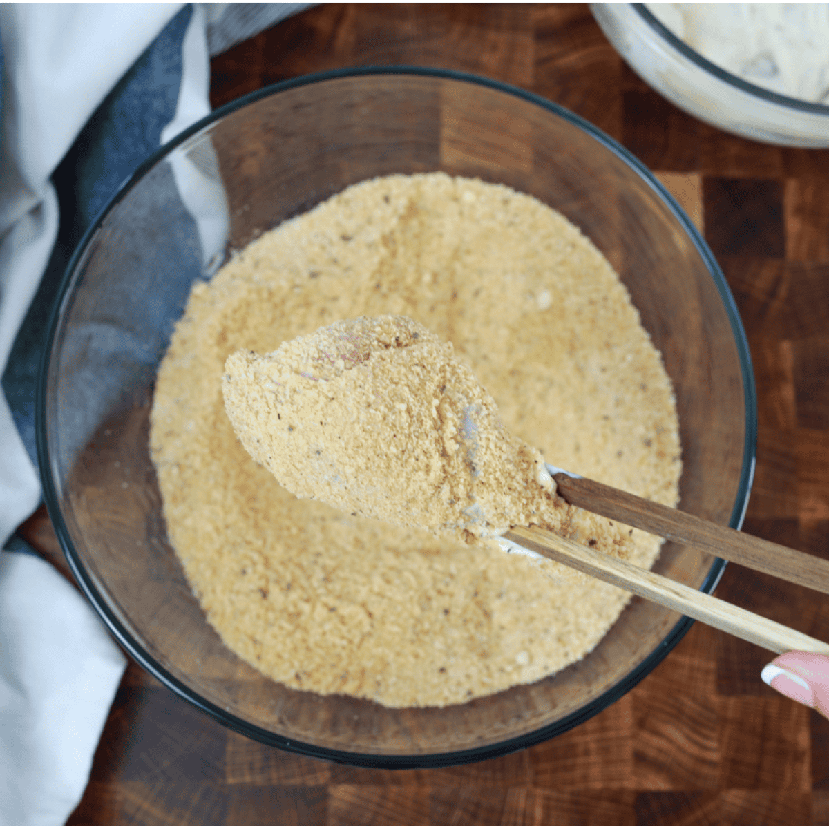 Whisking eggs in one bowl and mixing crushed pork rinds, almond flour, and seasonings in another bowl for keto drumstick coating preparation